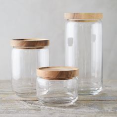 three glass jars with wooden lids on a table