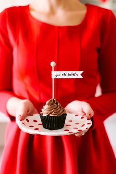 a woman in a red dress holding a cupcake with a sign on it that says you are sweet