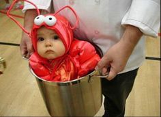 a man holding a bucket with a baby dressed as a bug in it's mouth