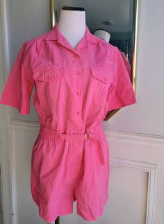 "This amazing vintage outfit by Ivory of Miami, Florida is ready to be worn again! This one-piece outfit is a vibrant pink all over. It has short sleeves and shorts on bottom with a slight split on sides of leg. There is elastic in the waist and a belt that buckles in front. The romper buttons down the front with a slightly pointed collar atop. There is a buttoning pocket on each side of chest.  Sized: Medium ( approx 6/8) waist: 16\" unstretched across front Chest: 19 across front length: 31\" Vintage Summer Overalls Jumpsuit, Retro Pink Jumpsuits And Rompers For Summer, Pink Retro Jumpsuits And Rompers For Spring, Retro Pink Summer Jumpsuits And Rompers, Pink Retro Summer Jumpsuits And Rompers, Retro Summer Jumpsuits And Rompers With Pockets, Retro Shortalls With Pockets For Spring, Vintage Cotton Shortalls For Spring, Vintage Short Sleeve Jumpsuits And Rompers For Spring