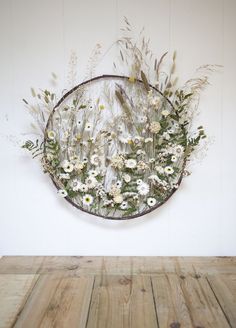 a wooden table topped with white flowers and greenery next to a wall mounted circular mirror