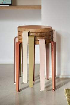 three wooden stools stacked on top of each other in front of a white wall