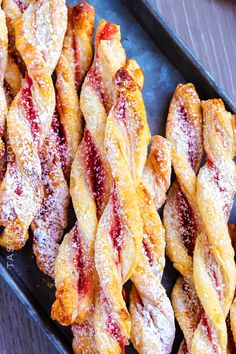 several pastries are lined up on a tray with powdered sugar and jelly toppings