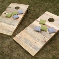 two pieces of wood sitting on top of grass next to each other with pillows and pillows