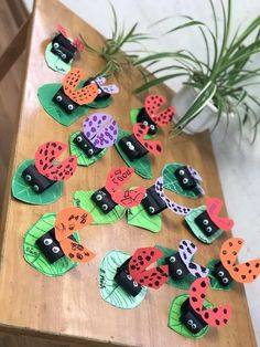 a wooden table topped with lots of ladybugs cut out of paper on top of leaves