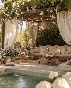 an outdoor seating area next to a pool with white flowers on the table and chairs