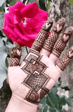 a woman's hand with henna on it next to a pink flower