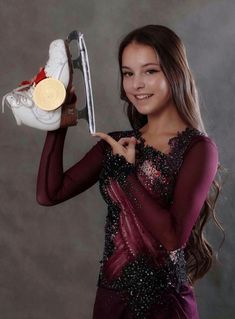 a woman holding up a pair of tennis shoes and a gold medal in her hand