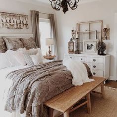 a bed sitting in a bedroom next to a wooden table with pillows on top of it