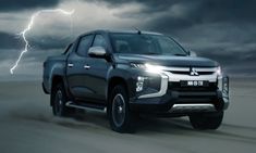 a silver truck driving down a road under a cloudy sky with lightning in the background