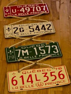 three different license plates hanging on a wood floor with rope and string attached to them