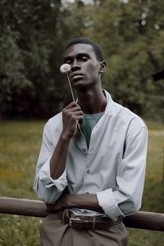 a man standing in front of a wooden fence holding a stick with a white substance on it