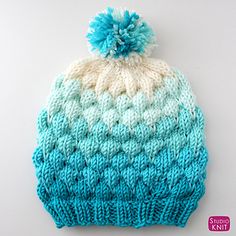 a blue and white knitted hat with a pom - pom on top