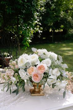 a vase filled with white and pink flowers on top of a table in the grass