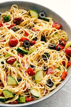 a pan filled with pasta and veggies on top of a white tablecloth