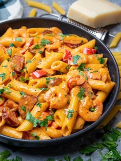 pasta with shrimp, tomatoes and parsley in a black bowl on a gray surface