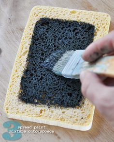 someone using a brush to spread paint on a piece of bread