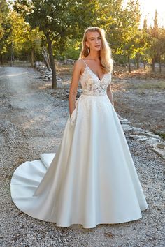 a woman in a wedding dress standing on gravel