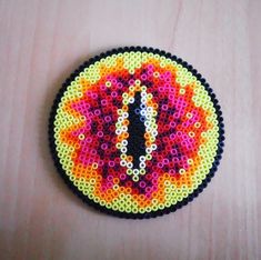 a clock made out of beads on top of a wooden table next to a wall