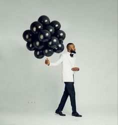 a man in a tuxedo holding black balloons