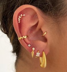 a woman wearing gold ear cuffs with diamond accents