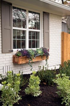 a white brick house with plants in the window boxes