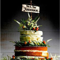 a multi layer cake with pineapples and greenery on top is displayed in front of a sign that reads mr & mrs anderson