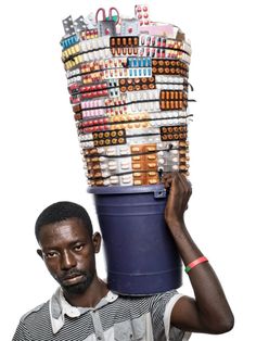 a man is carrying a large bucket full of items on his head and holding it over his head