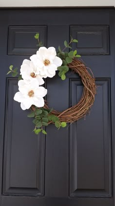 a wreath with white flowers hanging on the front door