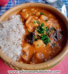 a wooden bowl filled with rice and some type of food on top of a table