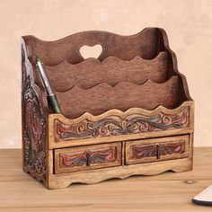 a wooden desk organizer with two drawers and a pen holder on the top, next to a phone