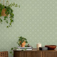 a green wall with a potted plant next to it on top of a wooden table