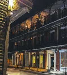 an empty street at night with lights on the windows and balconies lit up