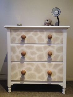 a giraffe print dresser with two drawers and a stuffed animal on the top