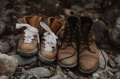 two pairs of hiking boots sitting on top of rocks next to each other with white laces