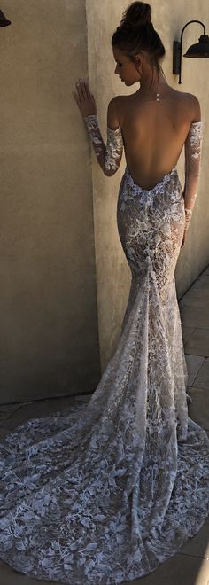 a woman in a white dress leaning against a wall with her back turned to the camera