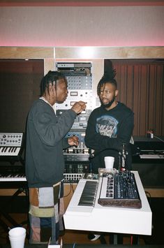 two men standing next to each other in front of a mixing desk with sound equipment