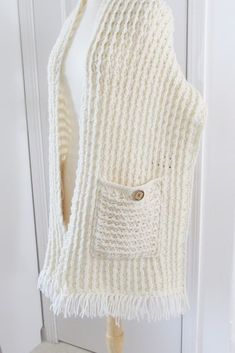 a white knitted vest hanging on a wall