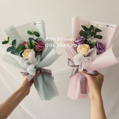 two hands are holding flowers in pastel colors