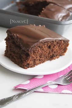 a piece of chocolate cake sitting on top of a white plate next to a fork