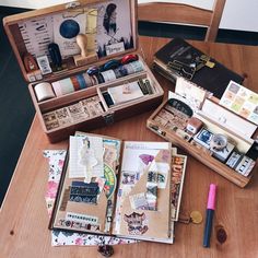 an open suitcase sitting on top of a wooden table filled with assorted crafting items