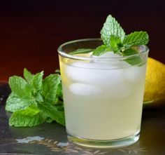 a glass filled with lemon ginger punch sitting on top of a table next to mint leaves