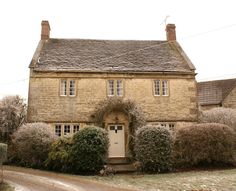 an old stone house with ivy growing on the front door and windows, along side a gravel road