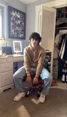 a young man sitting on top of a chair in a bedroom next to a closet