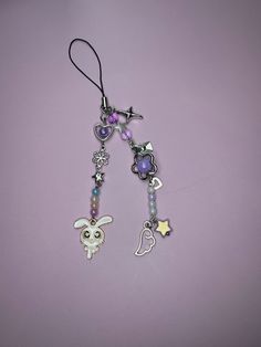 a pair of earrings with charms attached to them on a purple surface, one has an animal and the other has a star