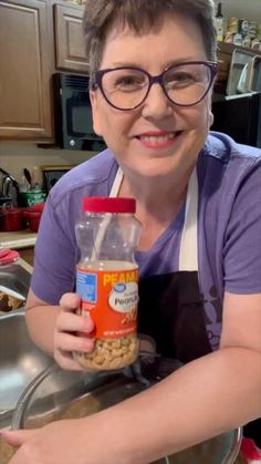 a woman in glasses holding a jar of food