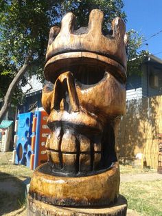 a wooden statue with a crown on it's head in front of a house