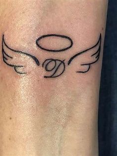 a small tattoo on the wrist of a woman with an angel wing and ball in it