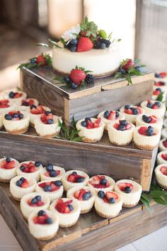 three tiered trays with cupcakes and berries on them are ready to be served