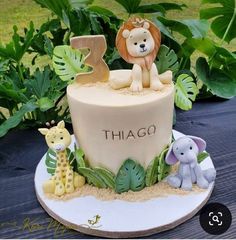 there is a cake decorated with animals and letters on the top, along with plants